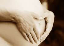 Schwangerenbauch gehalten von Händen in Herzform positioniert